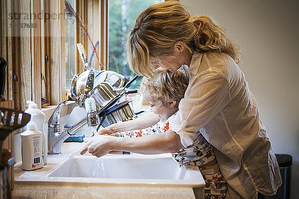 Mutter hilft Sohn beim Händewaschen an der Küchenspüle