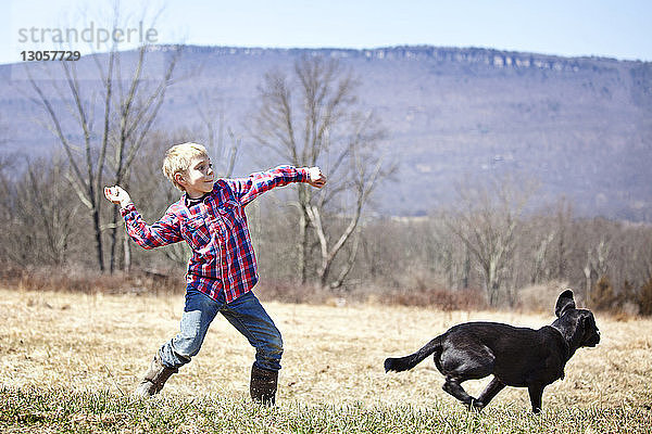 Junge spielt mit Hund auf dem Feld