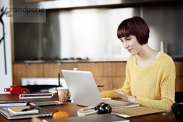 Konzentrierte Geschäftsfrau mit Laptop am Schreibtisch im Kreativbüro