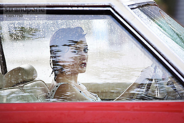Porträt einer Frau  die das Lenkrad hält  während sie im Auto sitzt