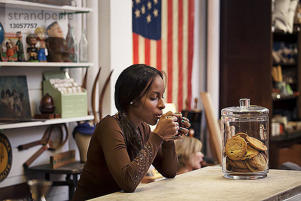Frau trinkt Kaffee  während sie in einem Café am Tisch sitzt