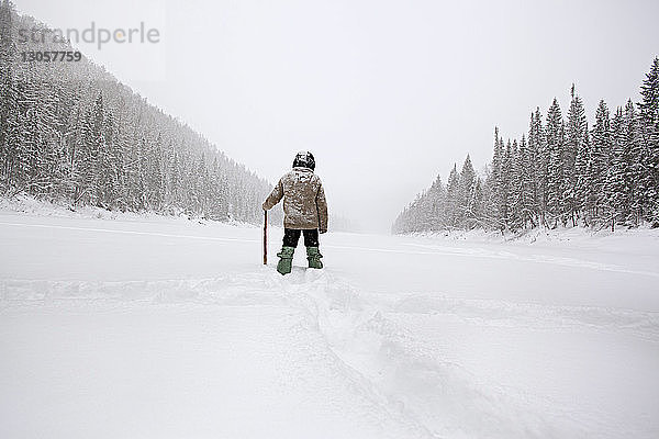 Rückansicht eines Mannes  der auf einem schneebedeckten Feld wandert