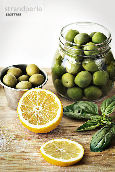 Grüne Oliven in Behältern durch geschnittene Zitronenscheiben auf Schneidebrett