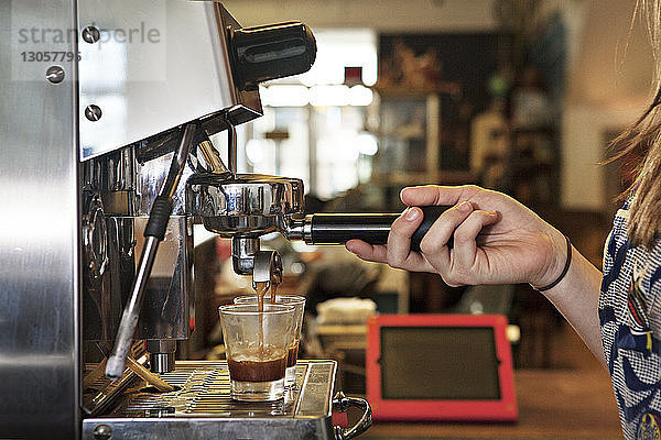 Ausgeschnittenes Bild einer Frau  die die Kaffeemaschine im Café benutzt