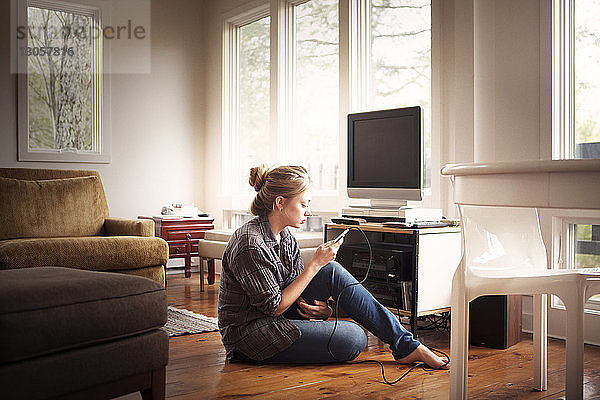 Frau benutzt Mobiltelefon  während sie zu Hause sitzt