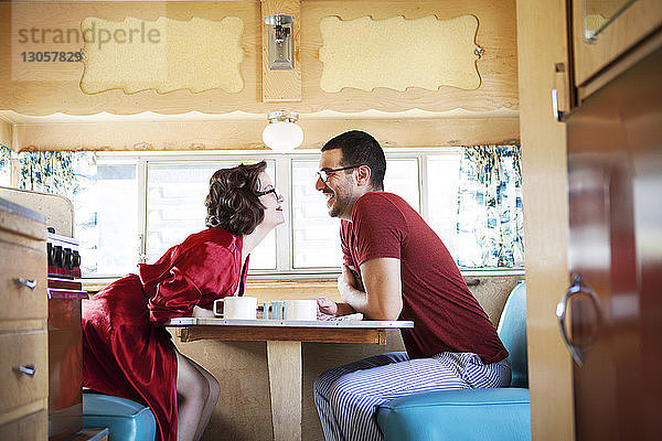Seitenansicht fröhliches Paar am Tisch sitzend im Wohnmobil