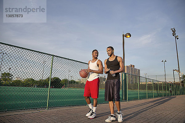 Basketballspieler unterhalten sich beim Laufen auf dem Platz gegen den Himmel