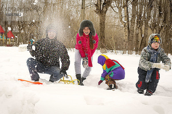 Fröhliche Familie spielt mit Schnee auf dem Feld