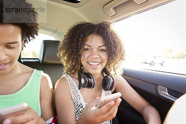 Porträt einer Frau  die telefoniert  während sie im Auto neben einem Freund sitzt