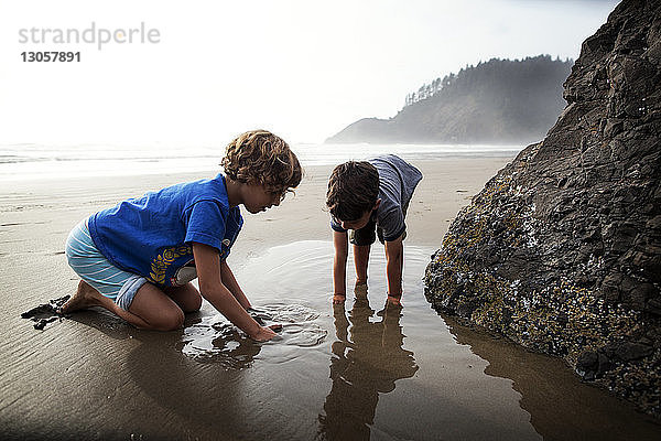 Kinder spielen mit nassem Sand am Strand