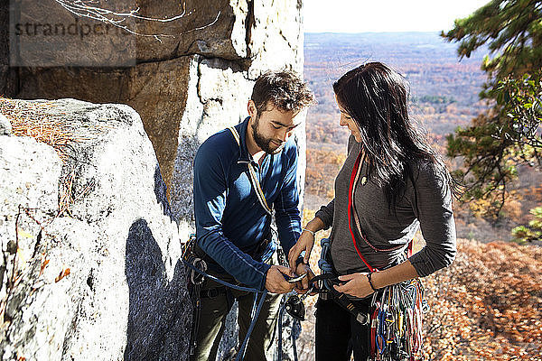 Mann hilft seiner Freundin beim Klettern