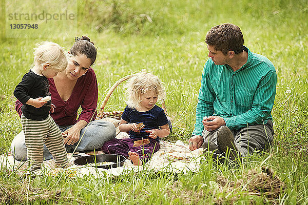Familie beim Essen auf einem Grasfeld sitzend
