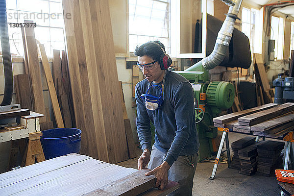 Männlicher Schreiner hält Holzbrett in der Werkstatt