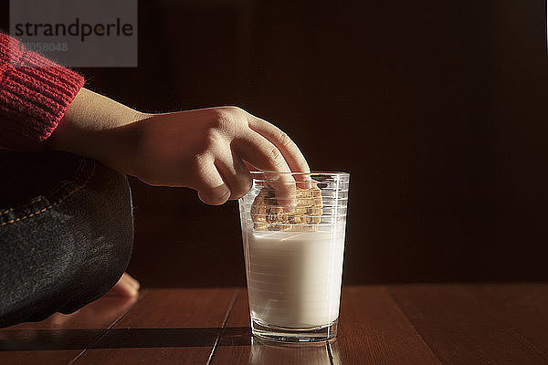 Ausgeschnittenes Bild eines Mädchens  das Kekse in Milch eintaucht