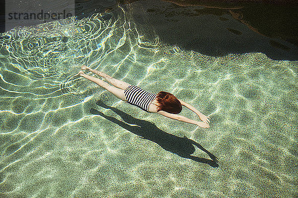 Rückansicht eines Mädchens  das an einem sonnigen Tag im Pool schwimmt