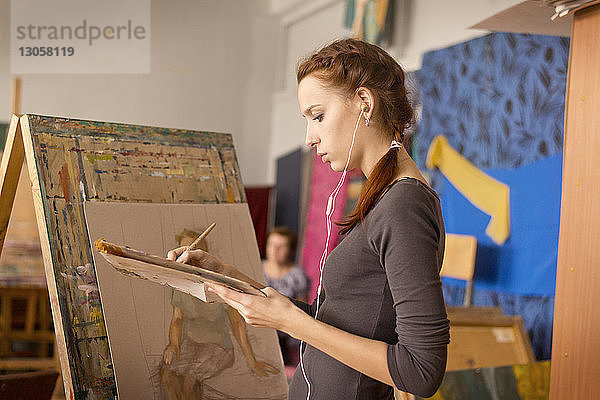 Junge Frau malt im Stehen im Kunstunterricht