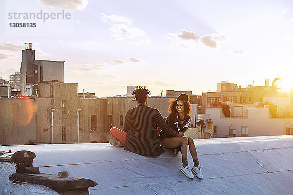 Glückliches Paar sitzt auf Stützmauer gegen Gebäude