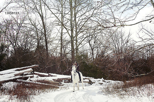 Frau zu Pferd auf Schneefeld sitzend
