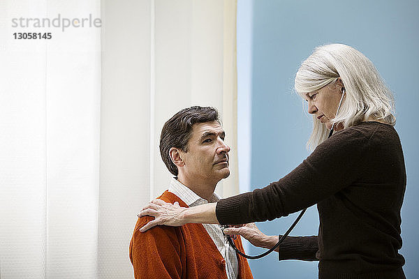 Arzt untersucht Mann mit Stethoskop im Krankenhaus