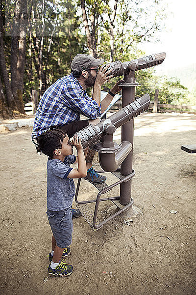 Vater und Sohn schauen durch Teleskope im Wald