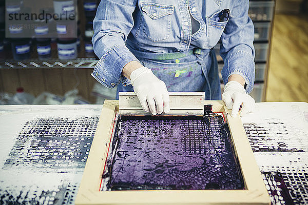 Mittelsektion einer Handwerkerin  die im Siebdruckverfahren ein Design auf Stoff druckt
