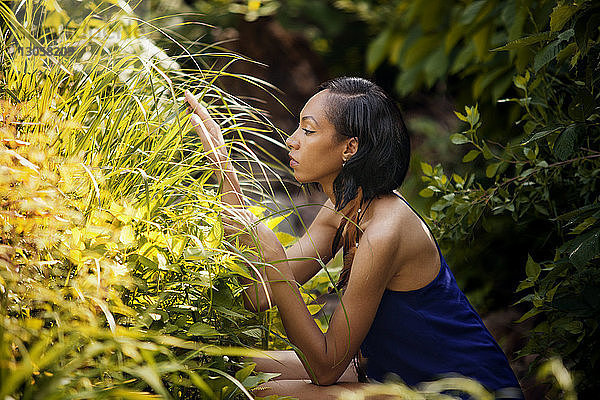 Seitenansicht einer Frau  die Pflanzen im Hof betrachtet
