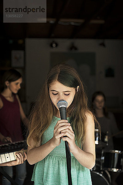 Mädchen singt mit Freunden im Hintergrund