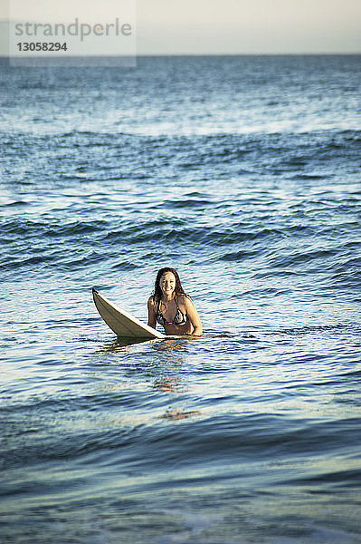 Lächelnde Frau beim Surfen im Meer