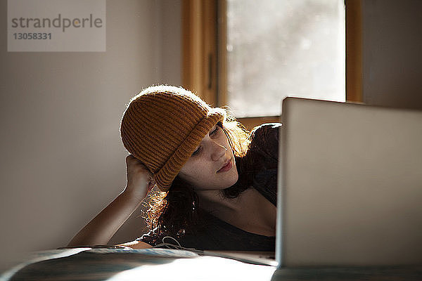 Teenagerin benutzt Laptop  während sie zu Hause im Bett liegt