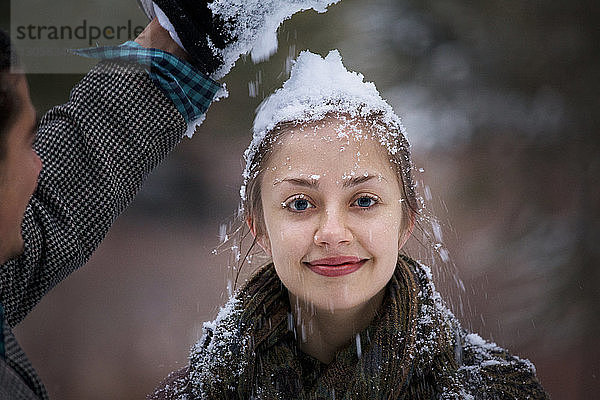 Mann drückt seiner Freundin Schnee auf den Kopf