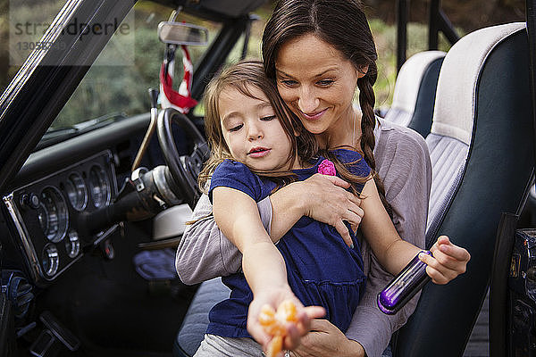 Glückliche Mutter hält Mädchen mit Orange im Pickup