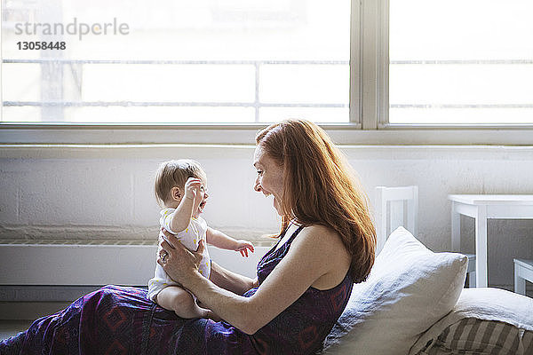 Seitenansicht einer Frau  die mit ihrer Tochter spielt  während sie zu Hause sitzt