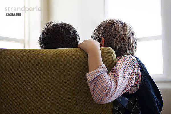 Geschwister  die zu Hause auf dem Sofa sitzen