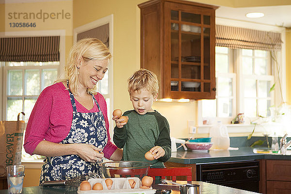 Glückliche Mutter und Sohn bereiten zu Hause in der Küche Essen zu