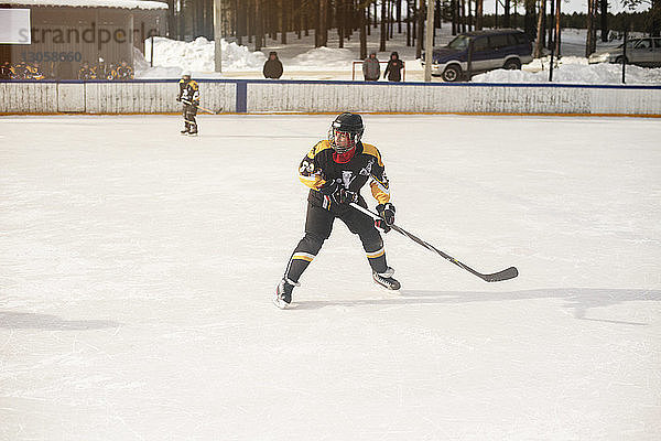 Junge spielt Eishockey an einem sonnigen Tag