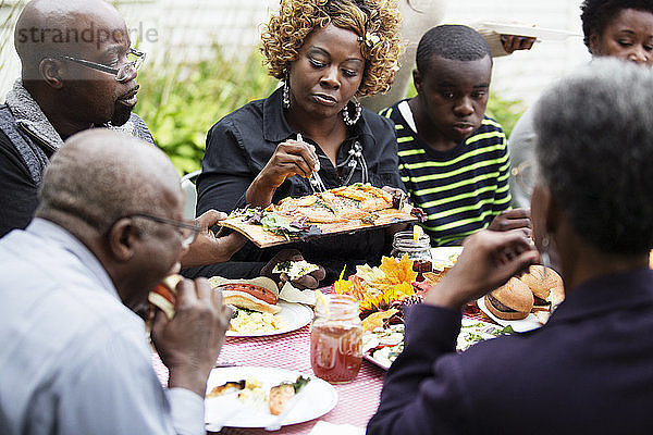 Familie und Freunde essen Essen  während sie am Tisch sitzen