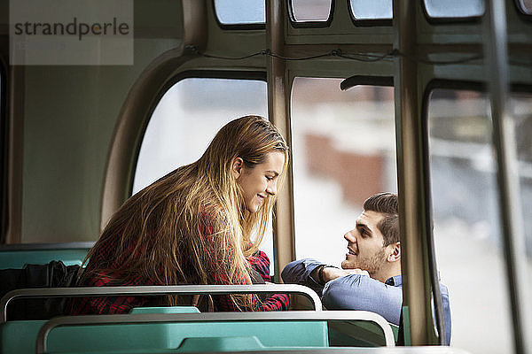 Mann sieht glückliche Frau an  während er sich an Straßenbahn lehnt