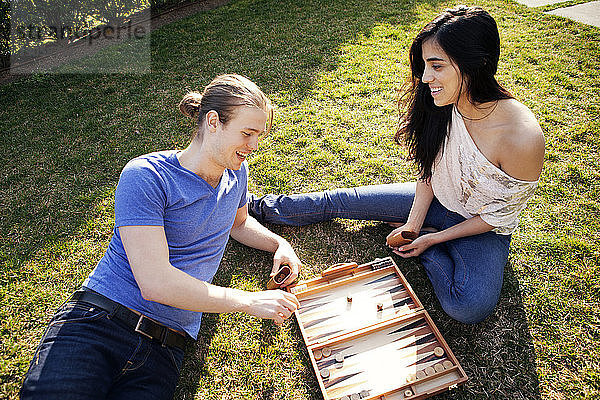 Hochwinkelaufnahme eines Backgammon spielenden Paares auf einem Rasenfeld