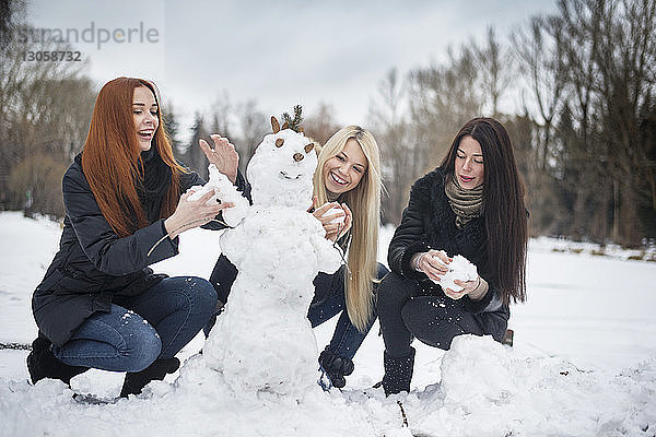 Freundinnen machen Schneemann auf dem Feld