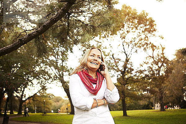Glückliche Frau kommuniziert am Telefon  während sie im Prospect Park steht