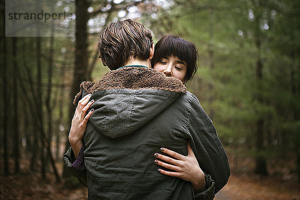 Paar umarmt sich im Wald stehend