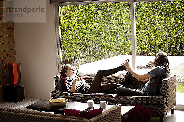 Mann massiert Frauenfüße  die zu Hause auf dem Sofa liegen