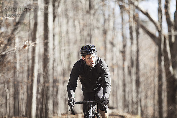 Fahrrad fahrender männlicher Sportler auf Straße im Wald