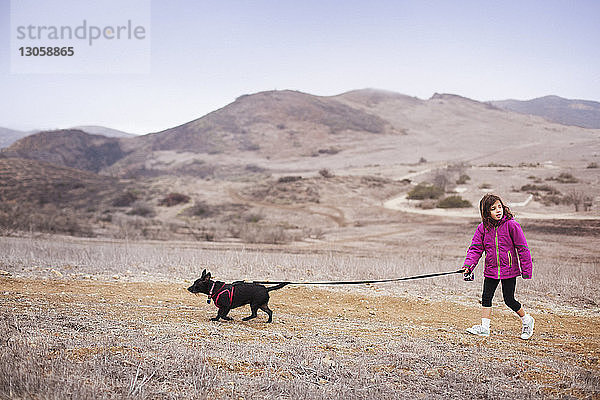 Mädchen mit Hund beim Spaziergang auf dem Feld