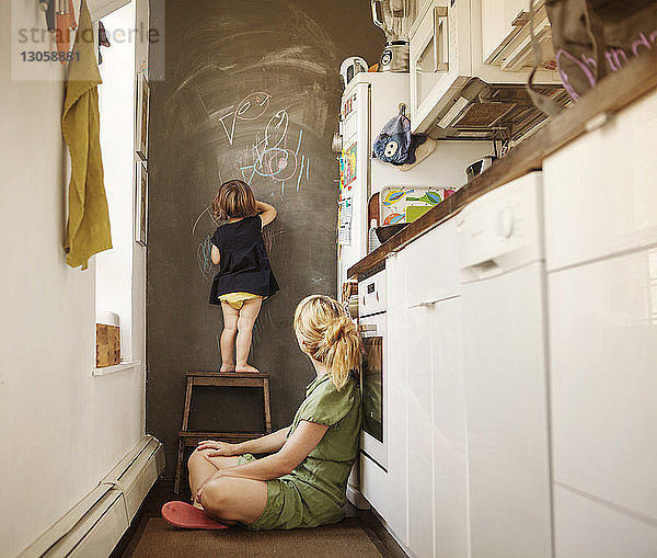 Tochter schreibt von zu Hause sitzender Mutter an die Wand