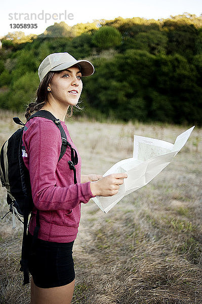 Seitenansicht einer Wanderin  die die Karte hält  während sie auf dem Feld steht