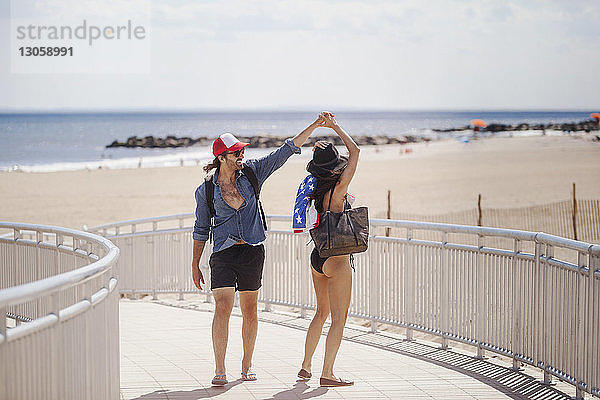 Glückliches Paar tanzt in den Sommerferien auf der Strandpromenade