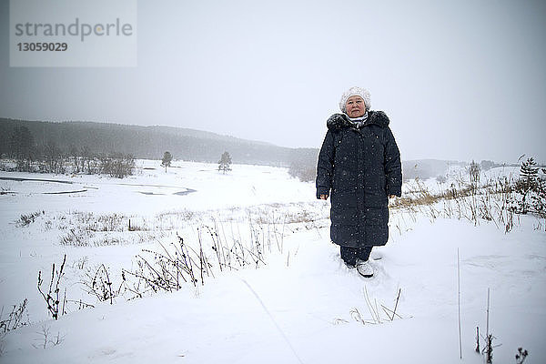 Bildnis einer Frau im Stehen auf schneebedecktem Feld vor klarem Himmel