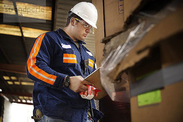 Niedriger Blickwinkel auf die Kontrollkästchen eines männlichen Arbeiters in einer Recycling-Anlage