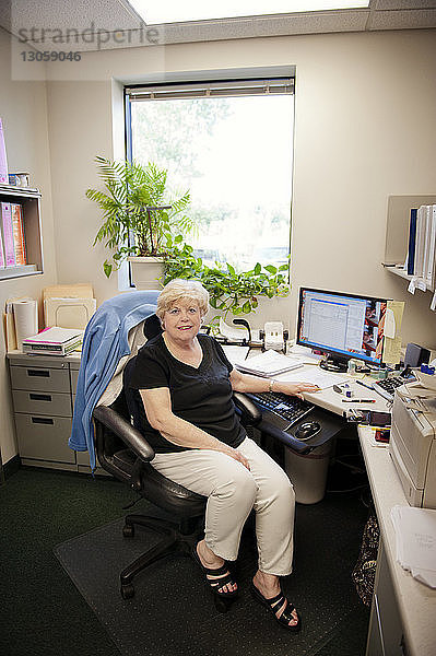 Porträt einer Geschäftsfrau  die im Büro am Tisch sitzt